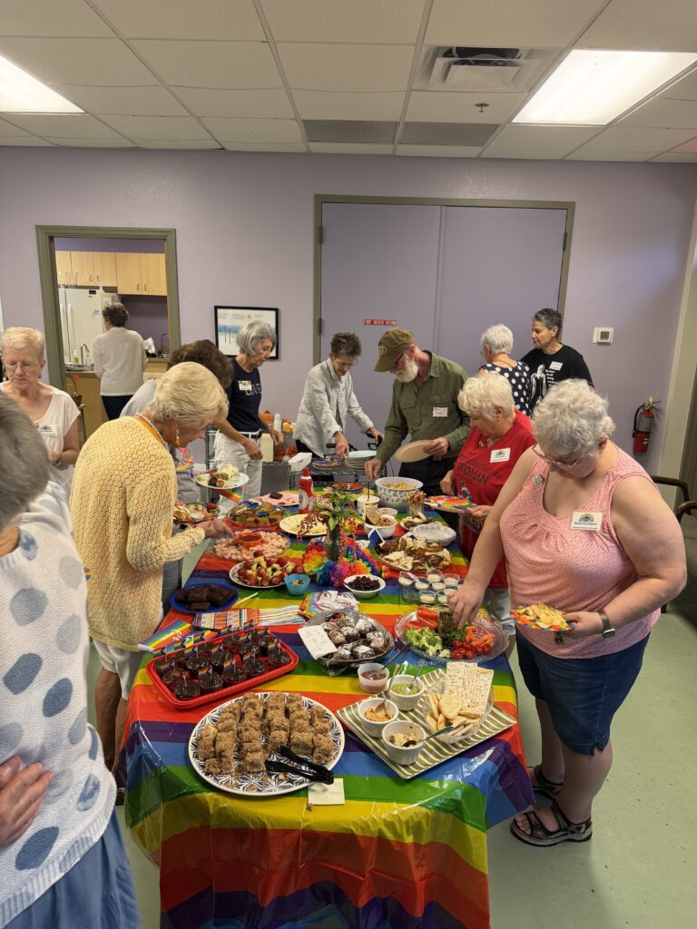 Members helping themselves to food from the rainbow-covered table.